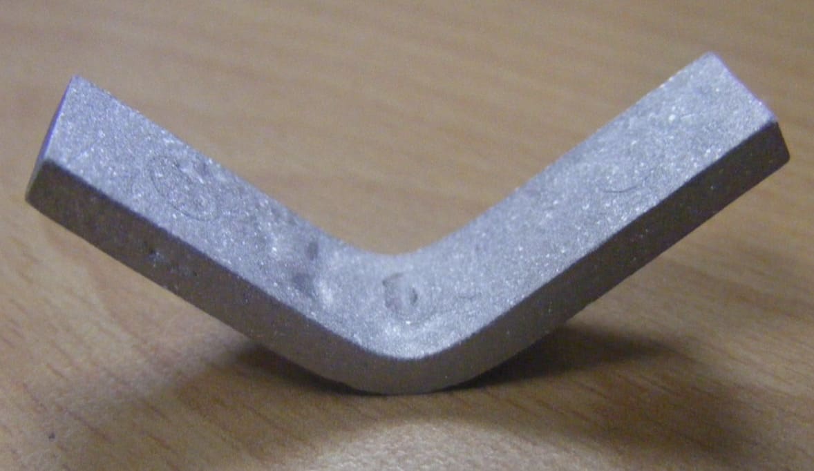 Bent metallic specimen after test